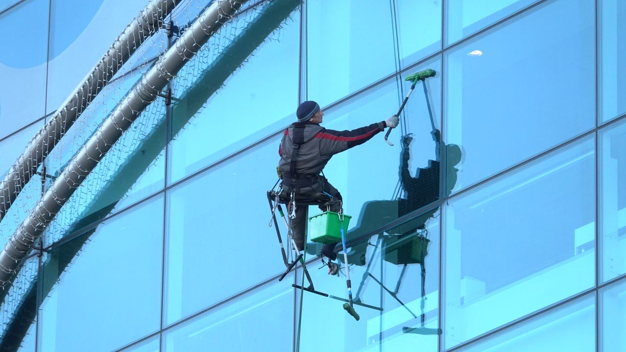 Un laveur de vitres intervient sur une tour en verre, en garantissant un résultat impeccable.